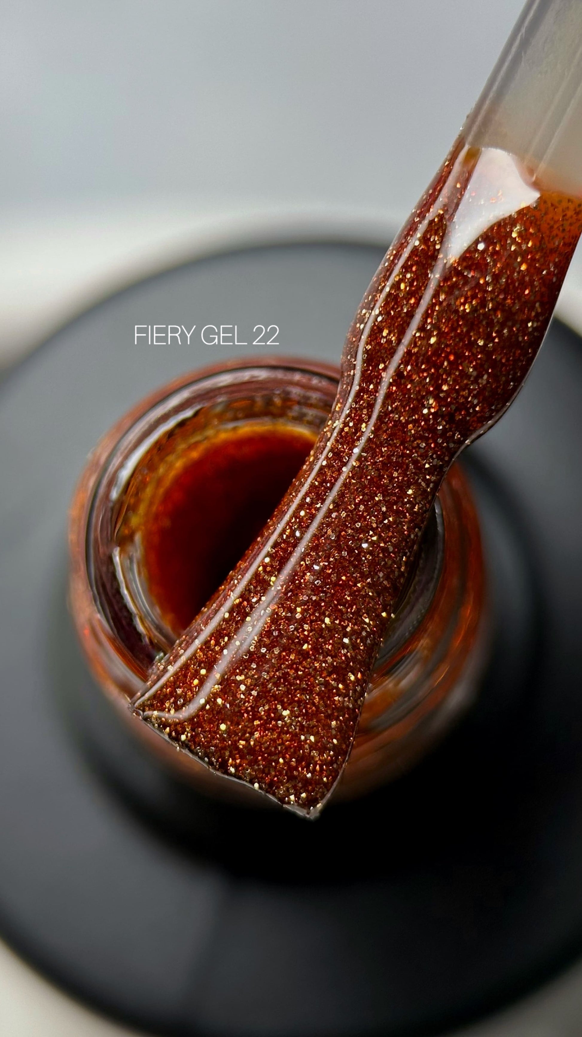A close-up view of a bottle filled with Saga Fiery Gel #23 vibrant red glitter gel, showcasing its shimmering texture and rich color.