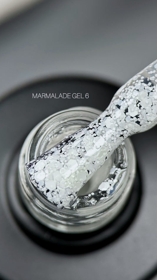 SAGA Professional Gel Polish Marmalade 06 – milky white gel polish with multicolored flakes in a 9ml bottle for delicate, playful nail designs.