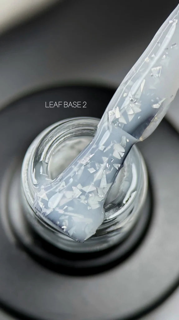 A hand applies white with flakes nail polish using a brush, showcasing the vibrant color and precise application technique.