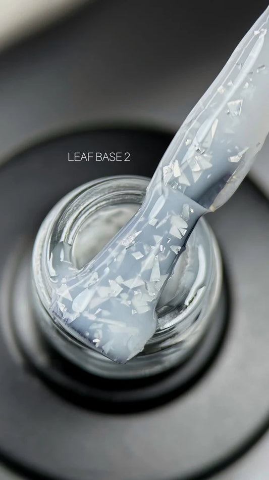 A hand applies white with flakes nail polish using a brush, showcasing the vibrant color and precise application technique.